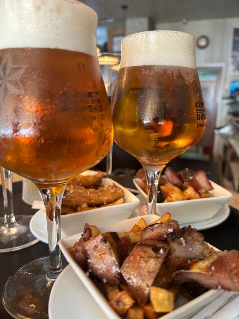 Mesa con tapas variadas y dos copas de cerveza